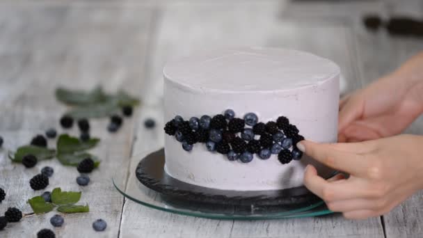 Suikerbakker versiert een mooie taart met bosbessen en bramen. — Stockvideo