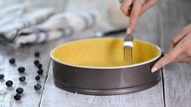 Kadın, çiğ hamur işi kutusunu bir çatalla her yere uzattı. Tarif konsepti.