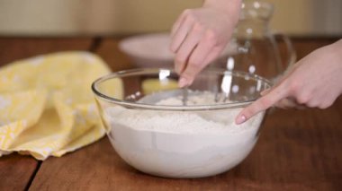 Kadın hamuru kaseye koyup yoğuruyor..