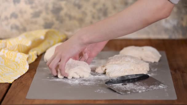 As mãos femininas cortam com um raspador uma massa de farinha amassada na superfície de trabalho . — Vídeo de Stock