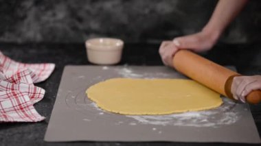 Kadın hamuru dolma kalemle yuvarlıyor. Turta için hamur çıkar..