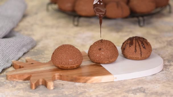 Fransk dessert Choklad Choux au Craquelin. Häll choklad över profiterolerna. — Stockvideo