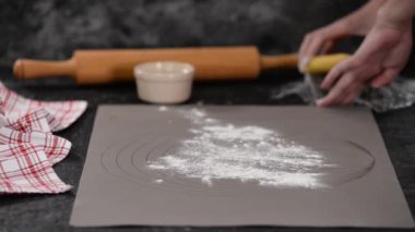 Kadın hamuru dolma kalemle yuvarlıyor. Turta için hamur çıkar..