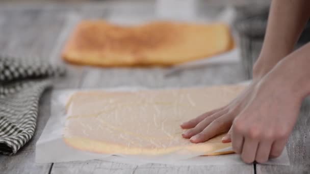 Manos femeninas pelando el papel de pergamino de la parte inferior de la torta de esponja . — Vídeos de Stock