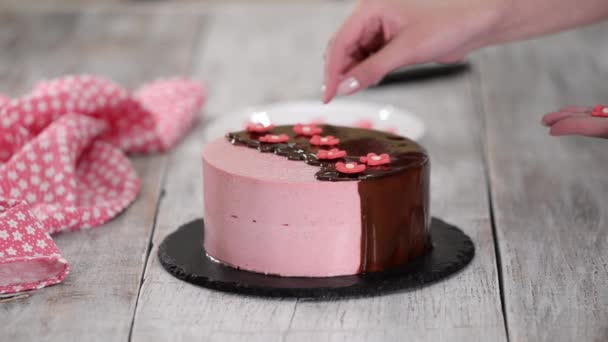 Mãos femininas decoram bolo de mousse de morango caseiro com flores de açúcar . — Vídeo de Stock