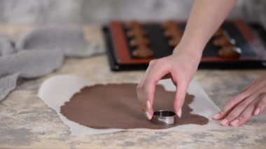 Çikolata hamurunu kesen kadın daireler çiziyor. Craquelin ile Choux çörekleri yapmak.
