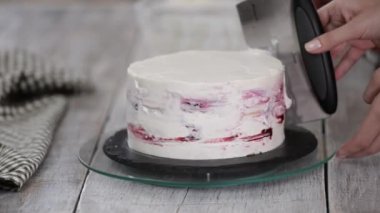Bir şekerci kremalı pasta hazırlar. Mutfaktaki beyaz masada tatlı. Ev yapımı, kek pişirme konsepti.