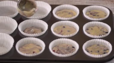 Çörek bardaklarına yabanmersini hamuru döküyorum. Yaban mersinli kek pişiren kadın..