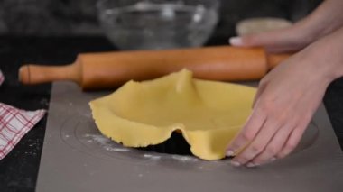 Mutfakta Fransız turtası yapan bir kadın. Aşçı bitmiş hamuru kalıba koyar..