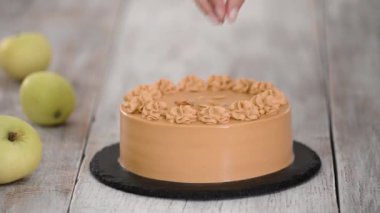Pasta şefi karamelli kekin üzerine badem püresi serpiyor..