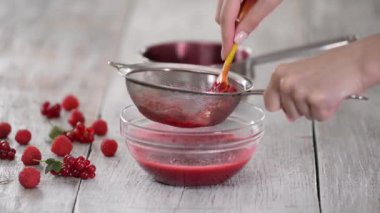 Şef kırmızı meyveleri cam kasede elek ile mutfağa itiyor..