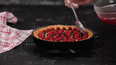 Meyveli ve jöleli kremalı tart yapan kadın. Çilekli tart..