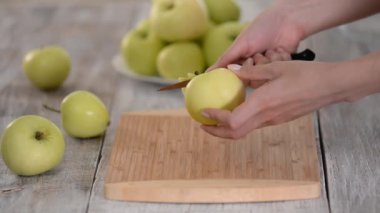 Aşçının elleri yeşil bir elmayı bıçakla soyar..