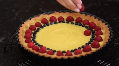 Puding ve jöleli çilekli tart yapan kadın..