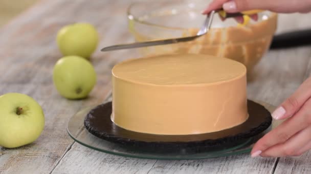 Le processus de décoration d'un gâteau avec couverture de crème au caramel. — Video