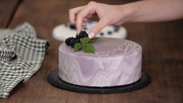 Vrouwen handen versieren een bessen mousse cake met verse bessen op de keukentafel. — Stockvideo