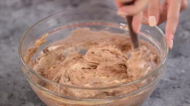 Bir kadın çikolatalı kek karışımını kasede bir spatulayla karıştırıyor..