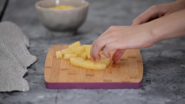 Женские руки режут ананас на мелкие кусочки. — стоковое видео