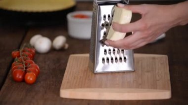 Ahşap masada peynir rendeleyen kadın..