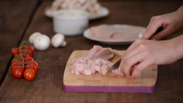 Female hands cutting chicken fillet on wooden chopping board. — Stock Video
