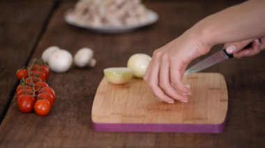 Aşçıların elleri bıçakla ahşap tahtadaki soğanı kesiyor..