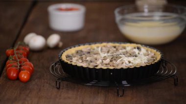 Adım adım kadın tavuk, mantar ve peynirli Quiche Lorraine yapıyor. Fransız mutfağı. Mozzarella peyniri turtanın üzerine serpilmiş.