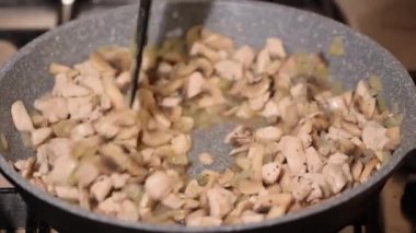 Kızarmış tavuk eti, mantar ve soğan kızartma tavasına yakın..