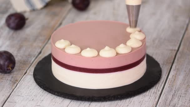 Pastry chef decorated a delicious plum mousse cake with whipped cream. — Stock Video
