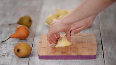 Kadınların elleri tahta kesme tahtasıyla armut kesiyor..