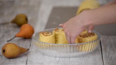 Baker armutlu çörekleri cam pişirme formuna koydu. Kadınlar hamur tatlısı yapar..