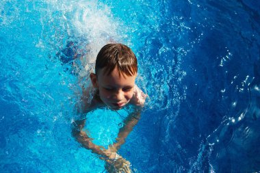 Mavi su havuz tropikal bir çare olarak denizin üzerinde oynayan mutlu çocuk. Yaz tatil kavramı. Sevimli çocuk havuzu suda yüzmek. Sıçramasına ve having fun yüzme havuzunda çocuk