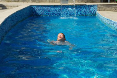 Mavi su havuz tropikal bir çare olarak denizin üzerinde oynayan mutlu çocuk. Yaz tatil kavramı. Sevimli çocuk havuzu suda yüzmek. Sıçramasına ve having fun yüzme havuzunda çocuk