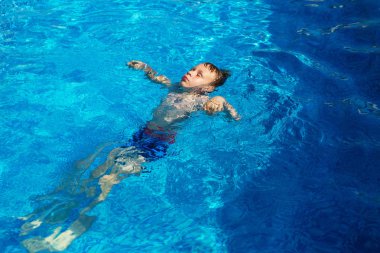 Mavi su havuz tropikal bir çare olarak denizin üzerinde oynayan mutlu çocuk. Yaz tatil kavramı. Sevimli çocuk havuzu suda yüzmek. Sıçramasına ve having fun yüzme havuzunda çocuk