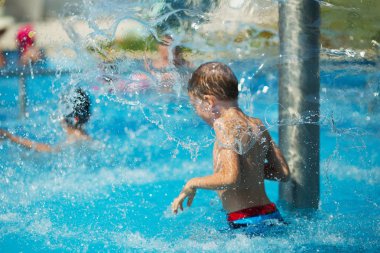 Mavi su havuz tropikal bir çare olarak denizin üzerinde oynayan mutlu çocuk. Yaz tatil kavramı. Sevimli çocuk havuzu suda yüzmek. Sıçramasına ve having fun yüzme havuzunda çocuk