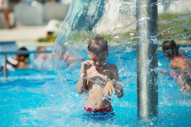 Mavi su havuz tropikal bir çare olarak denizin üzerinde oynayan mutlu çocuk. Yaz tatil kavramı. Sevimli çocuk havuzu suda yüzmek. Sıçramasına ve having fun yüzme havuzunda çocuk