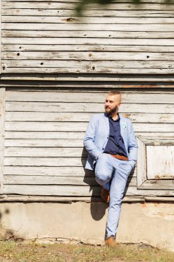 hipster genç adam uzakta kameradan arıyorum. moda damat eski bir ahşap duvar önünde duruyor