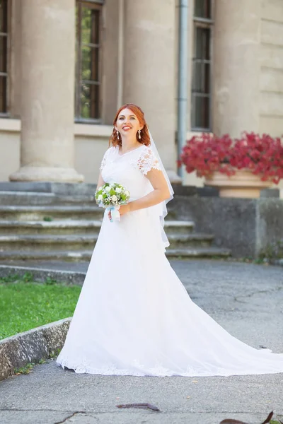 屋外の花束と赤毛の美しい花嫁 幸せな花嫁の屋外 彼女の結婚式の日でポーズ美しい花嫁 — ストック写真