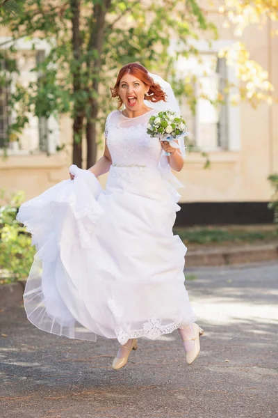 屋外の花束と赤毛の美しい花嫁 幸せな花嫁のジャンプと楽しいアウトドア 彼女の結婚式の日でポーズ美しい花嫁 — ストック写真