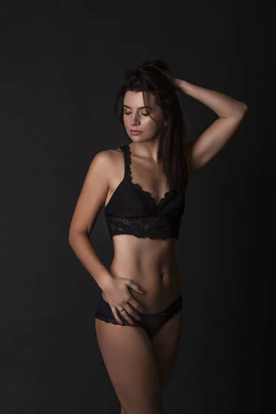 若い魅力的な女性のセクシーな体 暗い背景に黒いビキニでスポーティな美女 — ストック写真