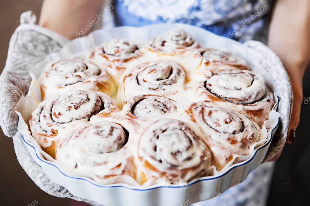 Cinabon rolls with cream cheese on the baking form in the women'