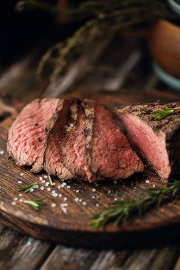 Sulu orta Beef Rib Eye biftek dilimleri ot ile ahşap tahta üzerinde