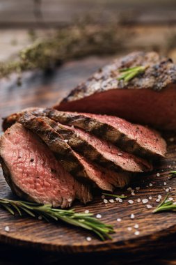 Sulu orta Beef Rib Eye biftek dilimleri ot ile ahşap tahta üzerinde
