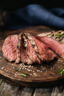 Sulu orta Beef Rib Eye biftek dilimleri ot ile ahşap tahta üzerinde