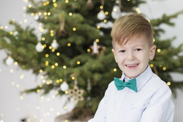 Niño feliz delante de un árbol de navidad decorado . — Foto de Stock