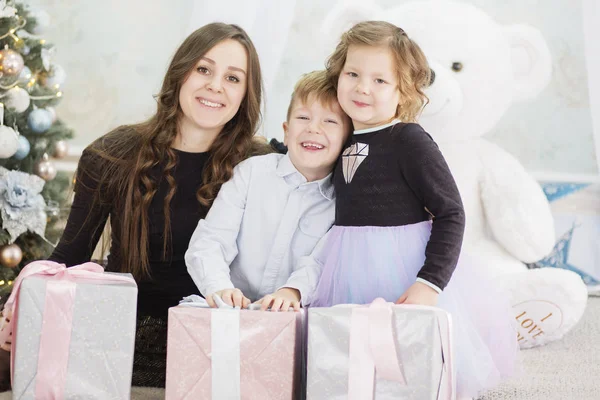 Mutter und ihre beiden kleinen Kinder mit Weihnachtsgeschenkschachteln. fa — Stockfoto