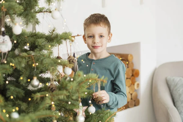 Kleine jongen versieren kerstboom met speelgoed en ballen. — Stockfoto