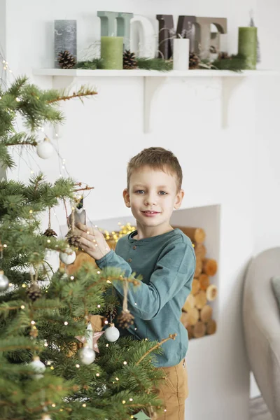 Liten pojke dekorera julgran med leksaker och bollar. (Kåll) — Stockfoto
