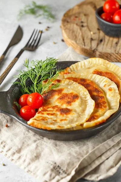 Heiße hausgemachte Pasteten auf einem schwarzen Teller serviert mit Tomaten — Stockfoto