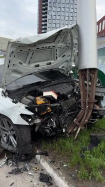 Ağır hasarlı bir araba, şehir yolunda kaza. Araba direğe çarpmış, ön taraf parçalanmış, kaput açık. Kaza kavramı, yoldaki tehlike ve sigorta..