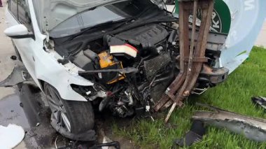 Ağır hasarlı bir araba, şehir yolunda kaza. Araba direğe çarpmış, ön taraf parçalanmış, kaput açık. Kaza kavramı, yoldaki tehlike ve sigorta..